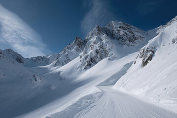 Obraz premium Towering snow-covered peaks display rugged alpine beauty beneath dramatic winter skies.