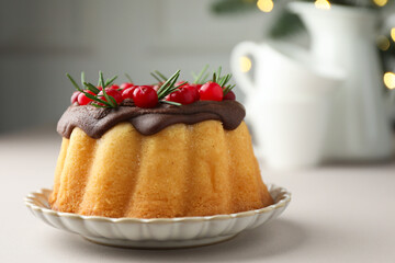 Tasty Christmas cake with cranberries on light table against blurred lights, closeup
