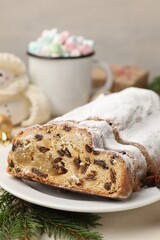 Cut traditional Stollen cake, drink and Christmas decor on white table, closeup
