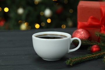 Aromatic coffee and Christmas decor on wooden table against blurred lights, closeup