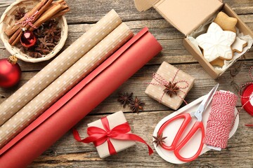 Festive packaging. Gift boxes, wrapping paper, twine, scissors, cookies and spices on wooden table, flat lay. Merry Christmas and Happy New Year