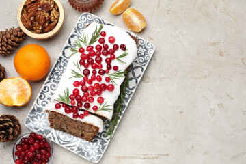 Tasty Christmas cake with icing, cranberries, nuts, tangerines and festive decor on light grey table, flat lay. Space for text