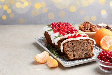 Tasty Christmas cake with icing, cranberries, nuts, tangerines and festive decor on light grey table against blurred lights, space for text. Bokeh effect