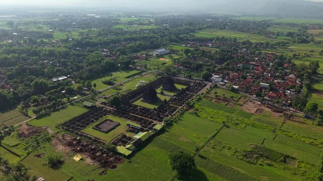 Aerial view of the ancient Candi Plaosan temple complex surrounded by lush greenery and rice fields, creating a striking contrast, Klaten Regency, Jawa Tengah, Indonesia.