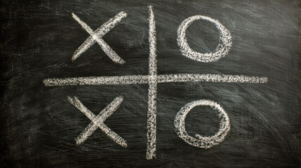 Tic tac toe game drawn with white chalk on a black chalkboard showing strategic moves and two 'x' and two 'o' symbols in classic grid pattern