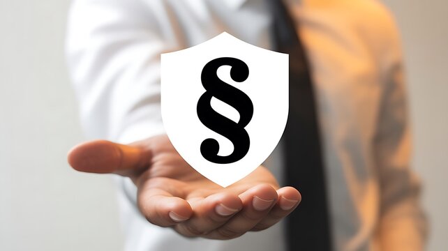 Hand holding a shield with a paragraph symbol representing legal protection security and justice concept