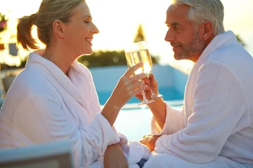 Fotobehang Beren Romance, sunset or couple in resort with toast, bonding or anniversary celebration on spa trip. Love, man or woman poolside with champagne cheers, honeymoon or summer evening in wellness getaway.  © peopleimages.com