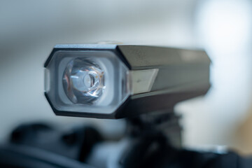 Close-up of a bicycle front light with a clear lens and LED housing, highlighting its compact design and illumination detail