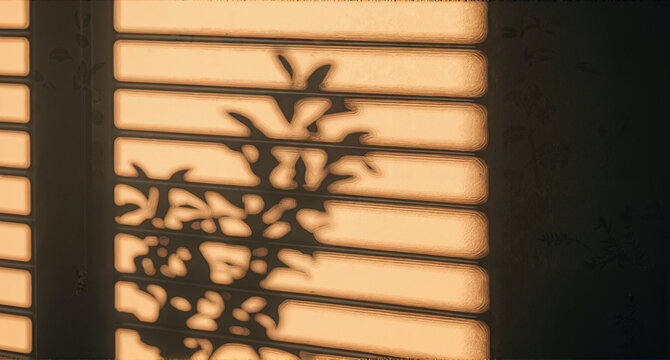 Sunlight streams through window blinds casting shadows of leaves creating a warm and inviting ambiance.