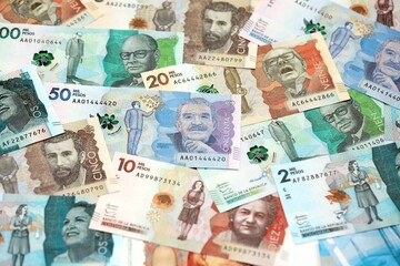 Colombian pesos money bills banknotes lies in big pile on table close up. Concept of finances and business in Colombia