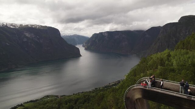 Aerial view of the Stegastein viewpoint overlooking the stunning Aurlandsfjord, a narrow fjord flanked by towering mountains with lush green vegetation, Aurland, Vestland, Norway.
