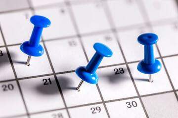 Calendar appointment blue thumbtacks in various dates on calendar diary