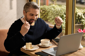 Mature man enjoys dessert and coffee while working on a laptop in a cozy cafe