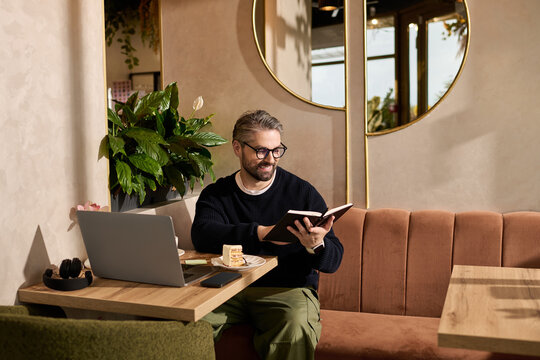 Mature man enjoying a cozy moment while reading in a stylish cafe