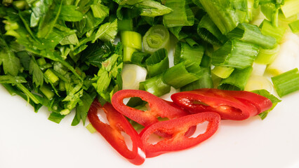 Sliced red chili pepper, green onion and parsley on a plate