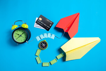 Credit card with alarm clock and antique compass with paper airplane on a blue background. Concept...