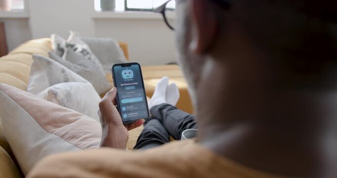 Adult Male using AI chatbot on Phone for Information, Sitting on Sofa at Home