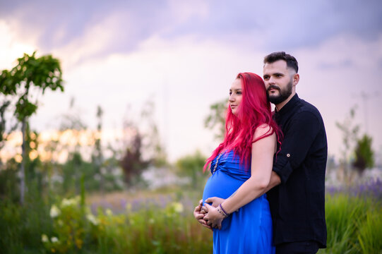 A couple stands outdoors among greenery as the man gently holds his pregnant partner’s belly. A calm, intimate moment of expecting a baby, filled with love and connection - Powered by Adobe