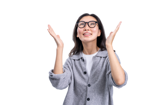 Smiling Asian woman with glasses and casual outfit looking upward with raised hands, closeup style on white background, concept of joy or inspiration