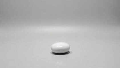 Purity in Light A single, smooth white pebble bathed in soft, diffused light. A single, perfectly smooth, pure white pebble resting on a subtle neutral surface. Illuminated by soft, diffused natural