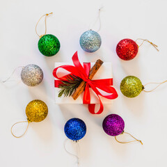 Festive christmas gift box surrounded by sparkling ornaments in a circular arrangement