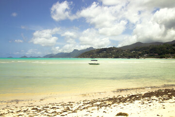 Obraz premium Anchored boat on tropical shoreline with mountains, Mahé, Seychelles