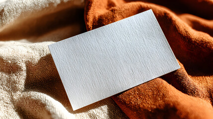 Blank white card on textured fabric perfect for design and message.