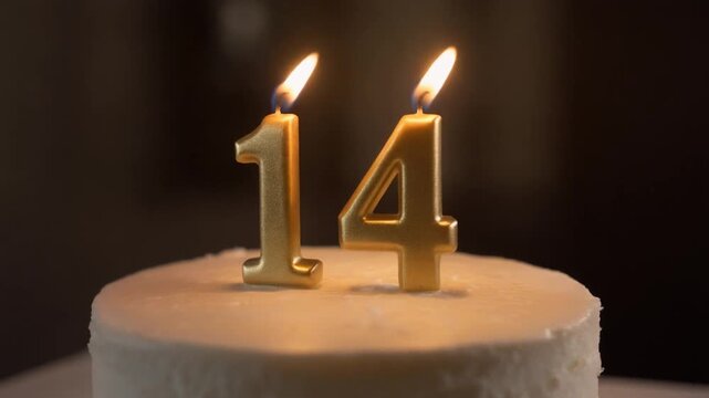 Glowing golden candles on a pristine white cake mark a significant 14th birthday celebration or a special anniversary milestone, symbolizing years of joy