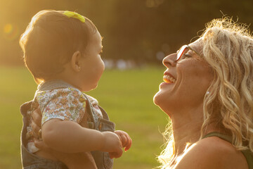 Happy grandma holding baby at sunset