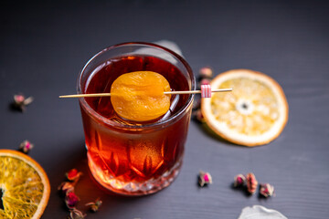 Whiskey sour cocktail decorated with dried apricot on a black table