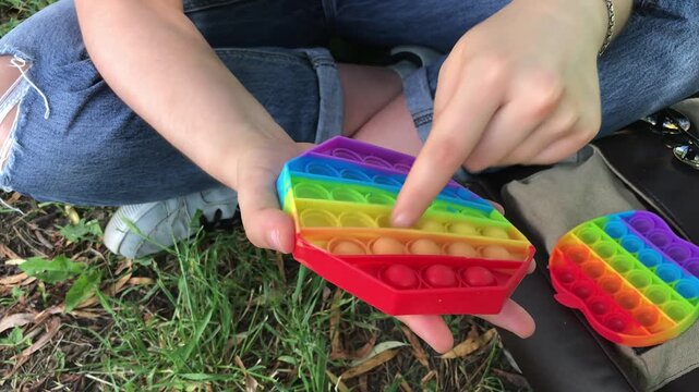 Colorful sensory fidget toy being pressed by a hand, showcasing playful interaction outdoors