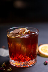 Whiskey sour cocktail decorated with dried orange on a black table