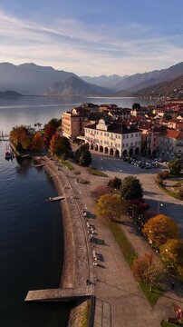 Cinematic aerial orbit of a Lake Maggiore village with red rooftops, autumn mountains and serene lakeside views, capturing the warm and atmospheric essence of northern Italy