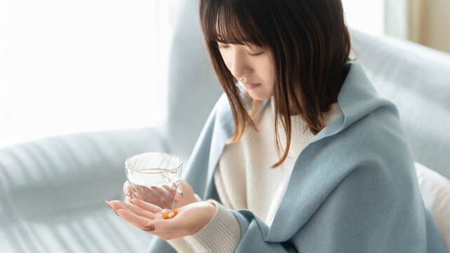 薬を飲む体調不良の女性