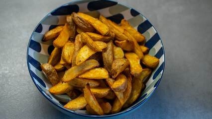 Homemade baked potato wedges in patterned bowl