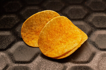 Close-up of several potato chips on a black baking tray