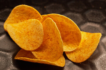 Close-up of several potato chips on a black baking tray