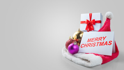 Greeting card of Merry Christmas with Christmas ornaments and a gift box with a Santa hat on a white background. Holiday greetings or winter themes. Concept of the Merry Christmas celebration