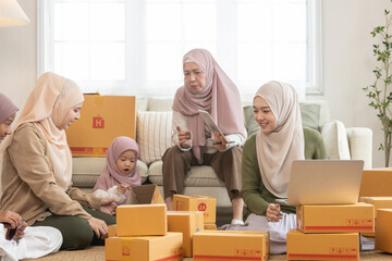 Muslim family running home based e-commerce business, packing boxes and using laptop together. Concept of teamwork, online selling, entrepreneurship and small family startup.