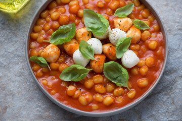 Plate of italian chicche di patate in tomato sauce with mozzarella balls and basil, horizontal shot, middle closeup