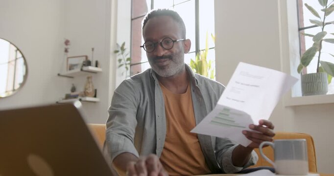 Mid Adult Man Working from Home Looking at Paper Finical Statements