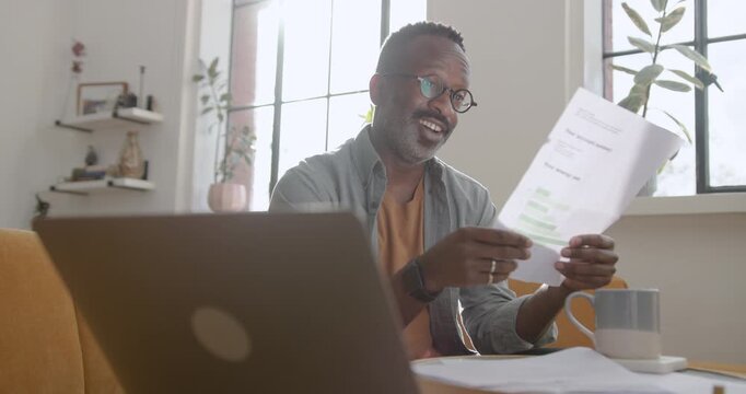 Mid Adult Man Working from Home Looking at Paper Finical Statements