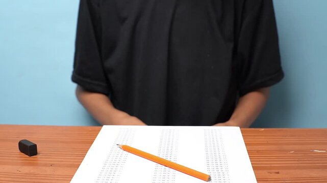 A student receives a small piece of paper thrown onto their desk during an exam, depicting a cheating attempt and academic dishonesty in a classroom setting.