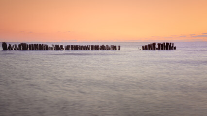 Sunset featuring groynes silhouetted against a calm sea and fading twilight.