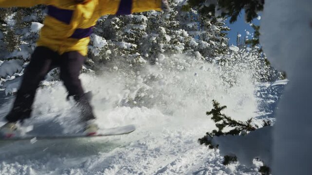 Snowboarder rides and jumps offpiste between pine trees. Backcountry at ski resort video 120p