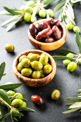 Olives assortment at olive cutting board with fresh olive tree branches.
