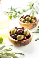 Olives and Olive oil in the bottle at white table.