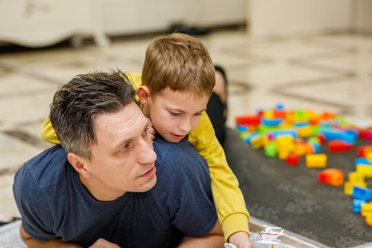 Loving father and son playing together on a luxurious tiled floor, embracing, laughing, and riding piggyback, demonstrating a strong family bond