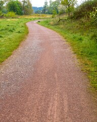 Obraz premium Winding gravel path through lush green meadow in spring