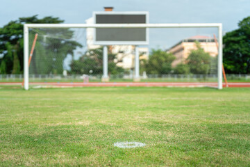 Football field with green grass ground, selective focus at penalty kick point as foreground and...
